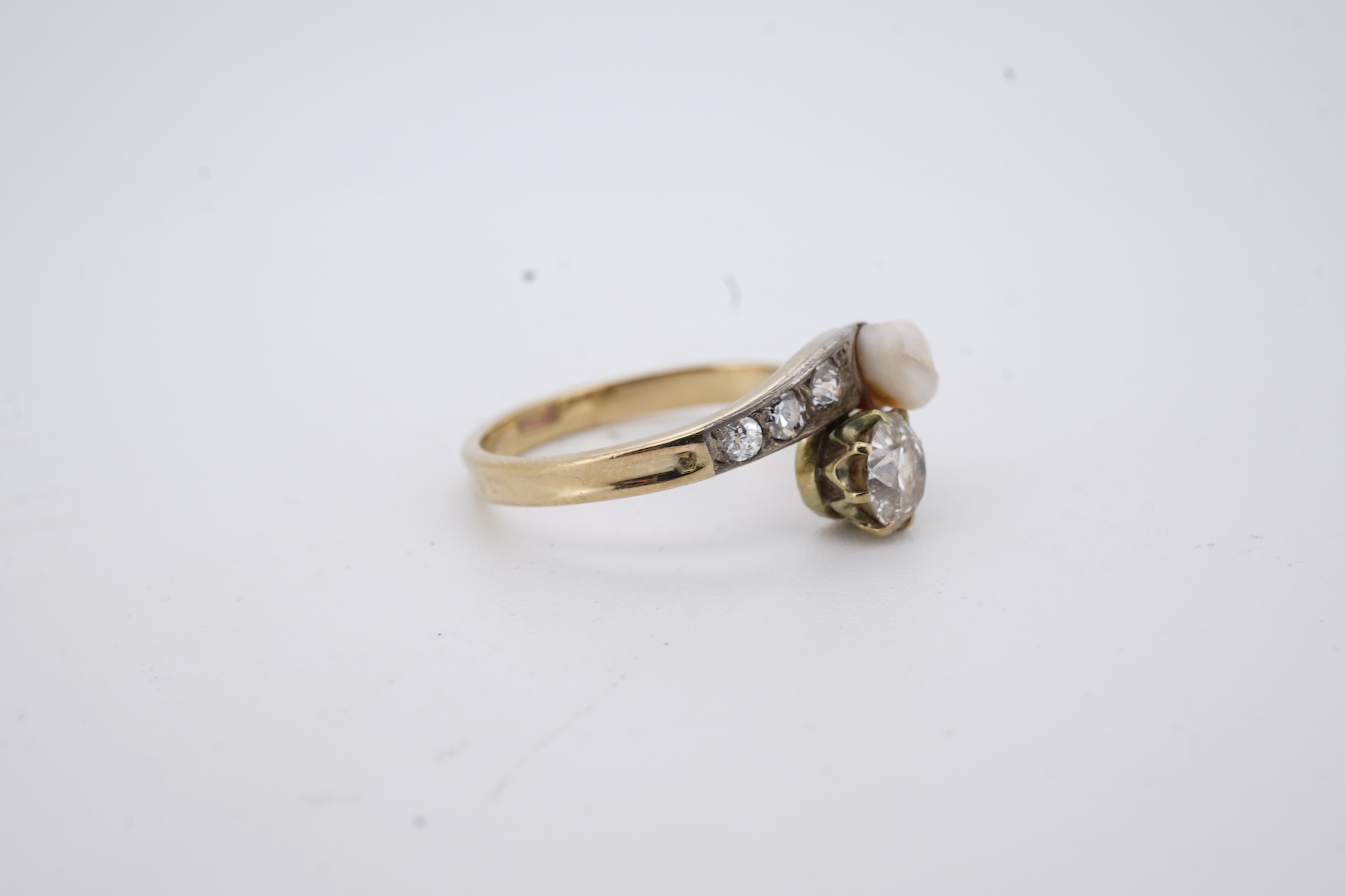 A yellow meta (stamped 18ct) cultured pearl and diamond set crossover ring, with six stone graduated diamond set shoulders, size M, gross weight 2.6 grams (pearl nacre a.f.).